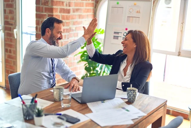 two people high-fiving at a desk
